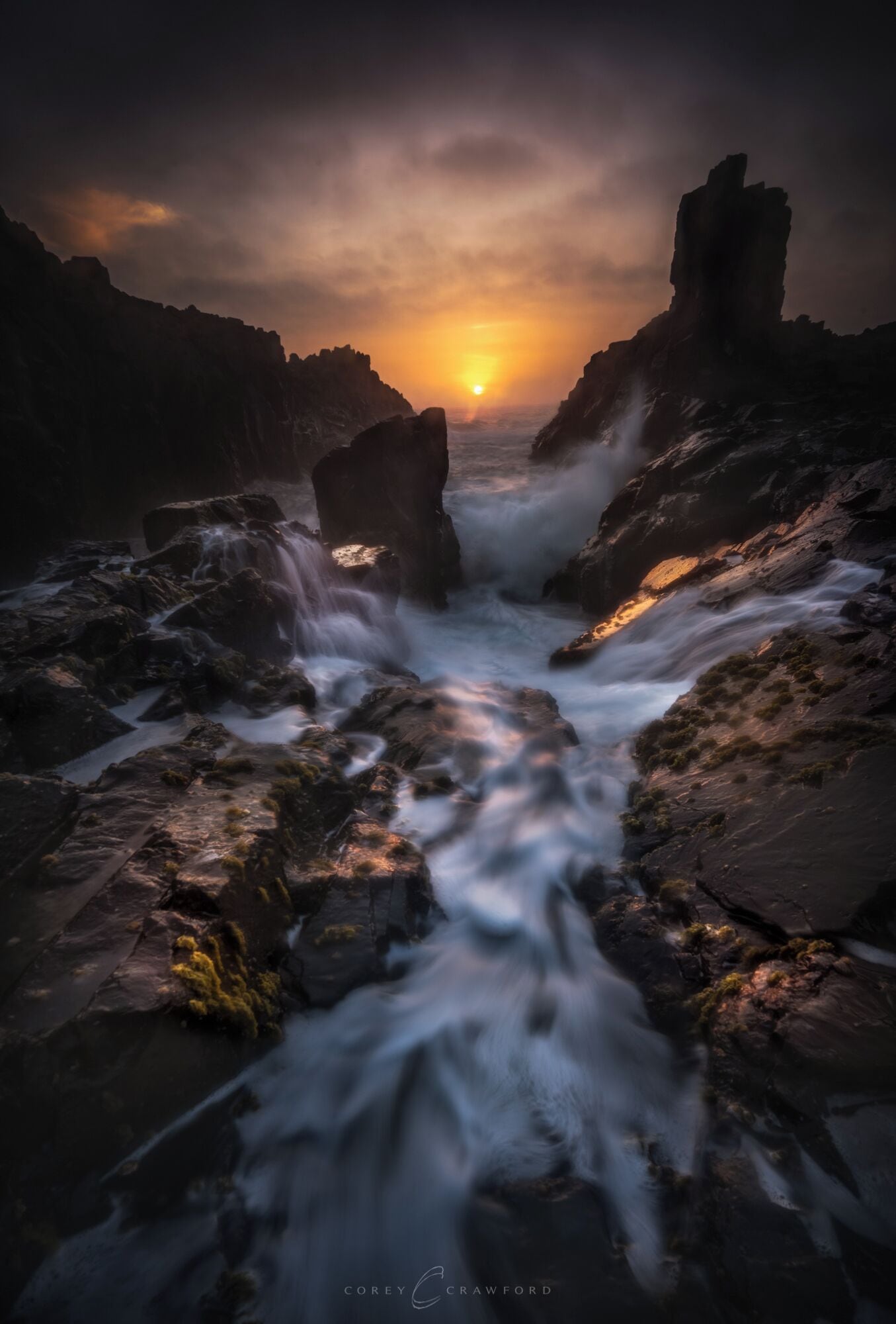 Litoral rochoso com uma cascata ao pôr do sol.