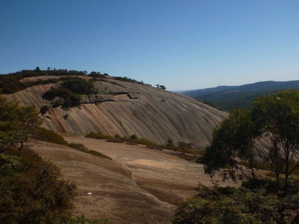 A large, eroded hill with sparse vegetation and a clear sky.