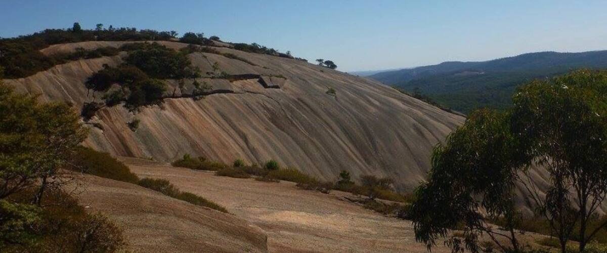 A large, eroded hill with sparse vegetation and a clear sky.