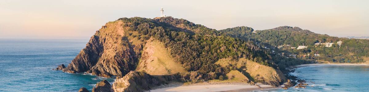 Aerial shot at sunrise over the ocean and white sand beach with swimmers and surfers enjoying summer