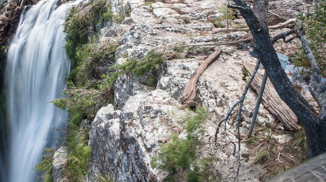 A waterfall cascading down a rocky cliff surrounded by sparse vegetation.