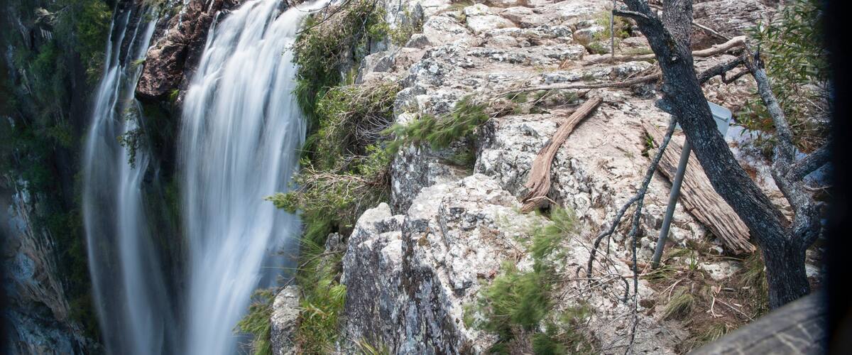 A waterfall cascading down a rocky cliff surrounded by sparse vegetation.