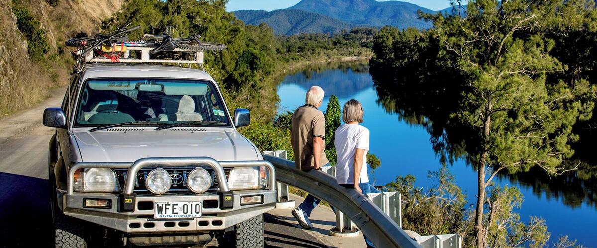 A silver SUV with a license plate WFE 010 parked by a lake with two people standing beside it.