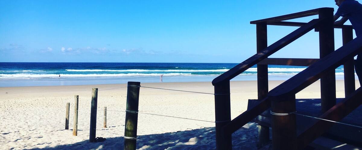 A wooden lifeguard tower overlooking a sandy beach with waves in the background.