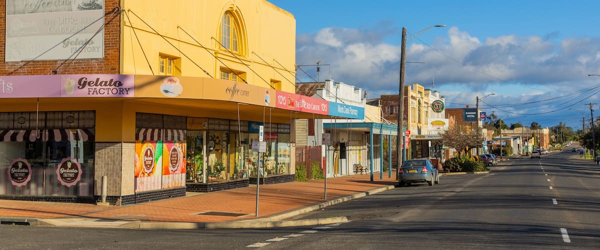 A street with shops including a pharmacy, gelato factory, and a toy store.