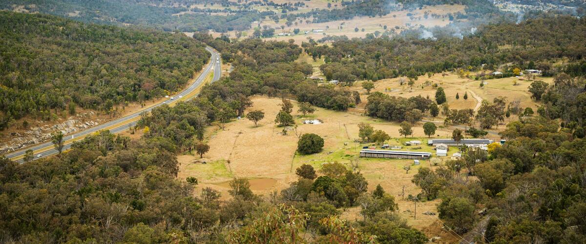 A winding road through a hilly landscape with scattered buildings and trees.