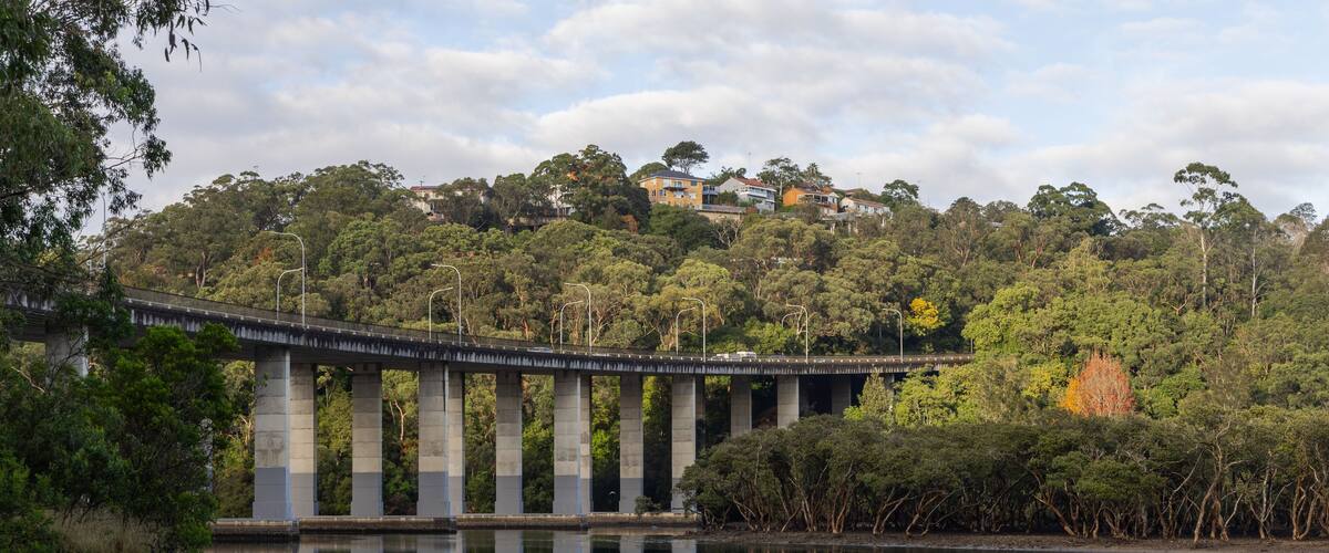 Un puente sobre un río tranquilo, con un paisaje de colinas boscosas al fondo.