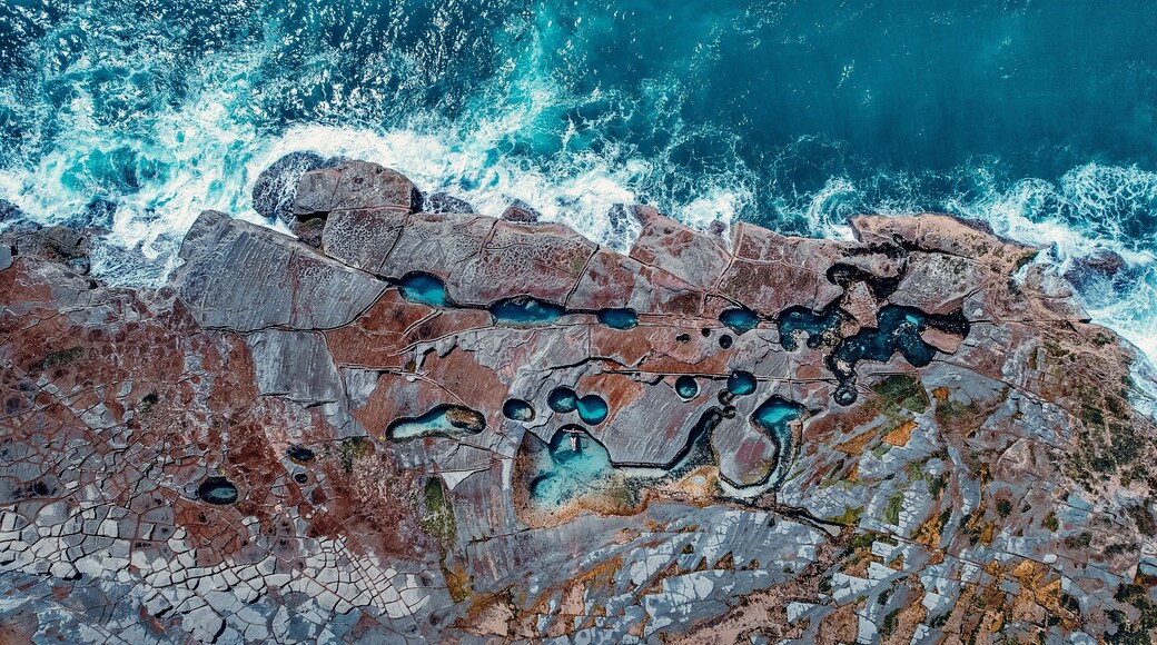A coastal landscape with rocky terrain and turquoise pools.