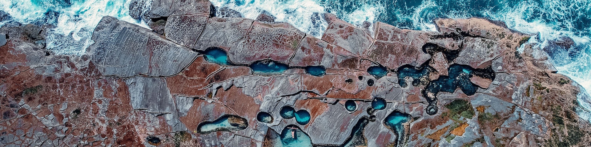 Un paisaje costero con terreno rocoso y pozas color turquesa.