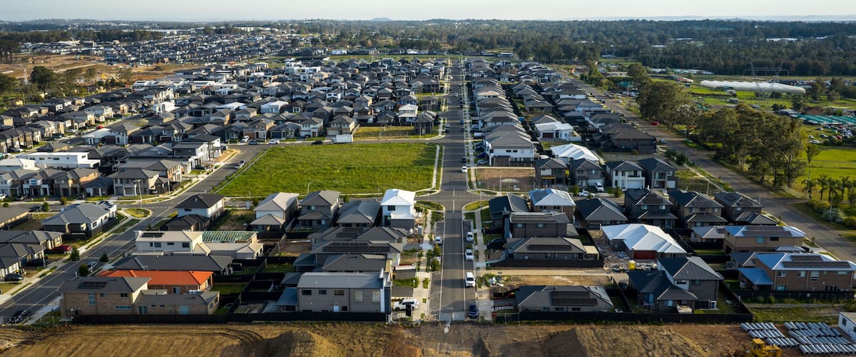 A residential area with houses, roads, and a large open field.