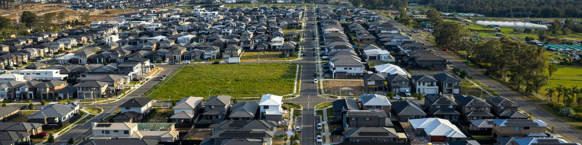 A residential area with houses, roads, and a large open field.