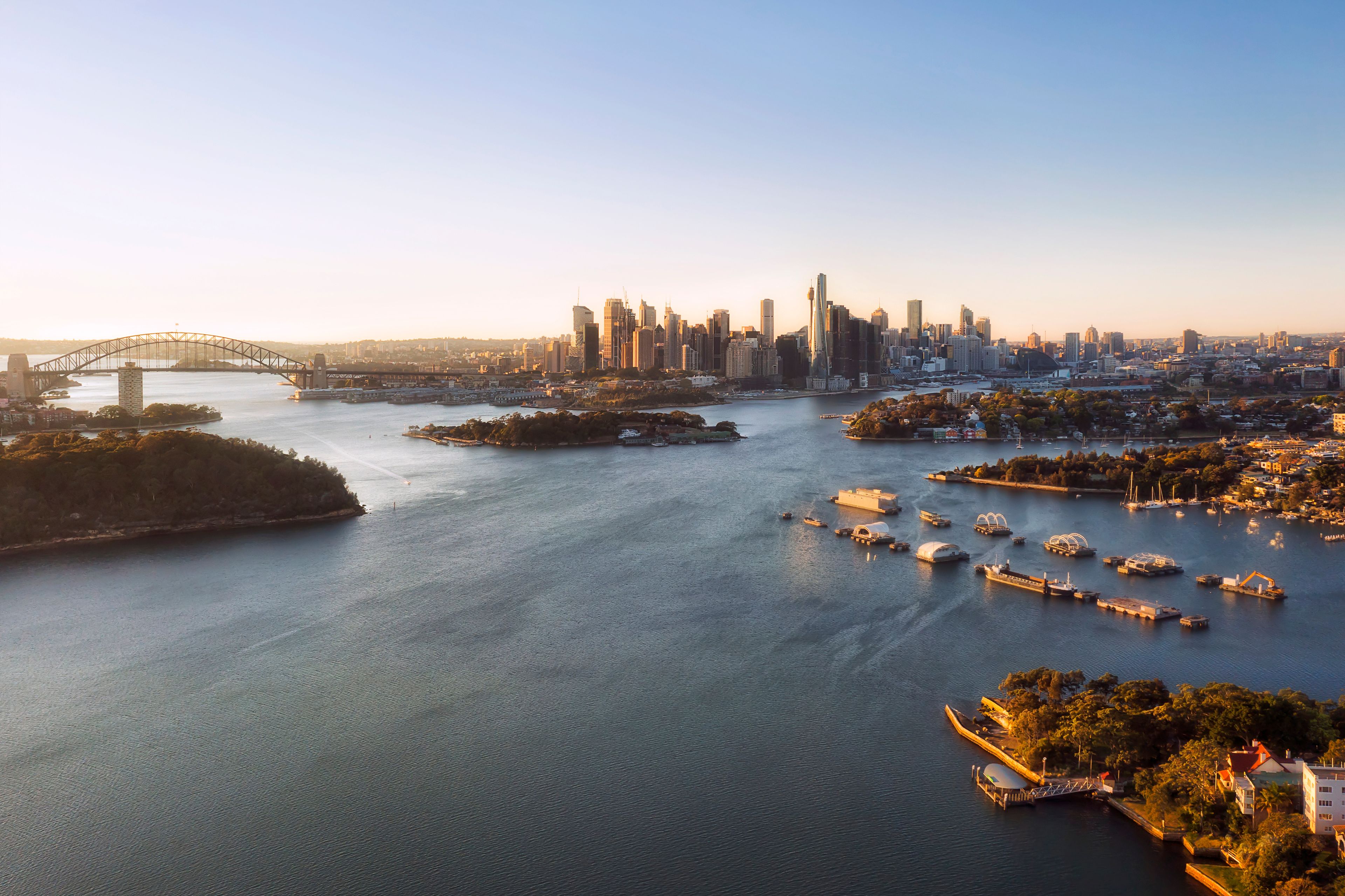 A city skyline with a prominent bridge, a marina with boats, and a river.