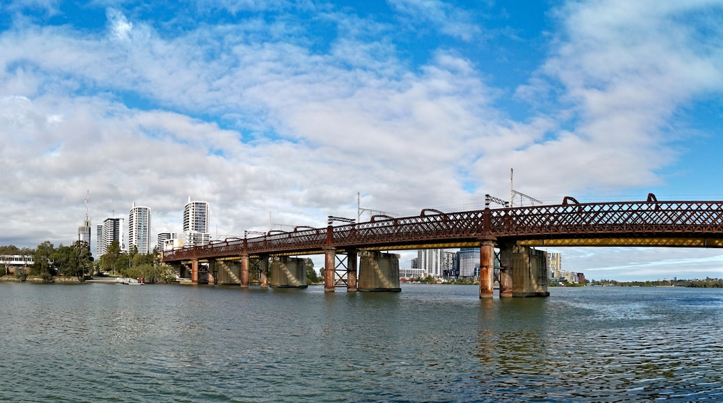 A bridge over a body of water with a city skyline in the background.