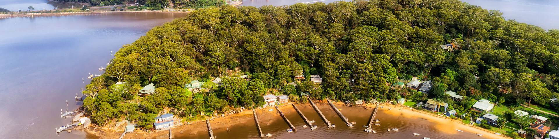 A river with a bridge, a forested island, and boats.