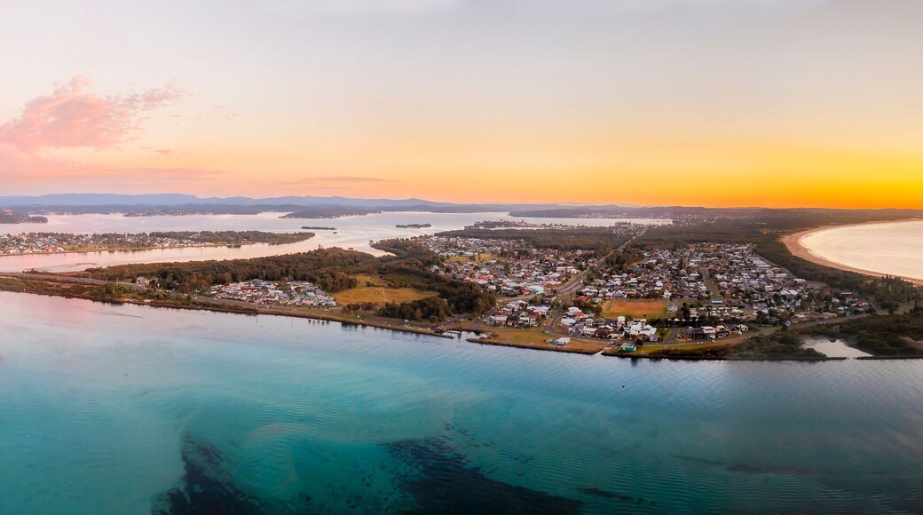 A coastal town with a bay, surrounded by forested areas and a large body of water.