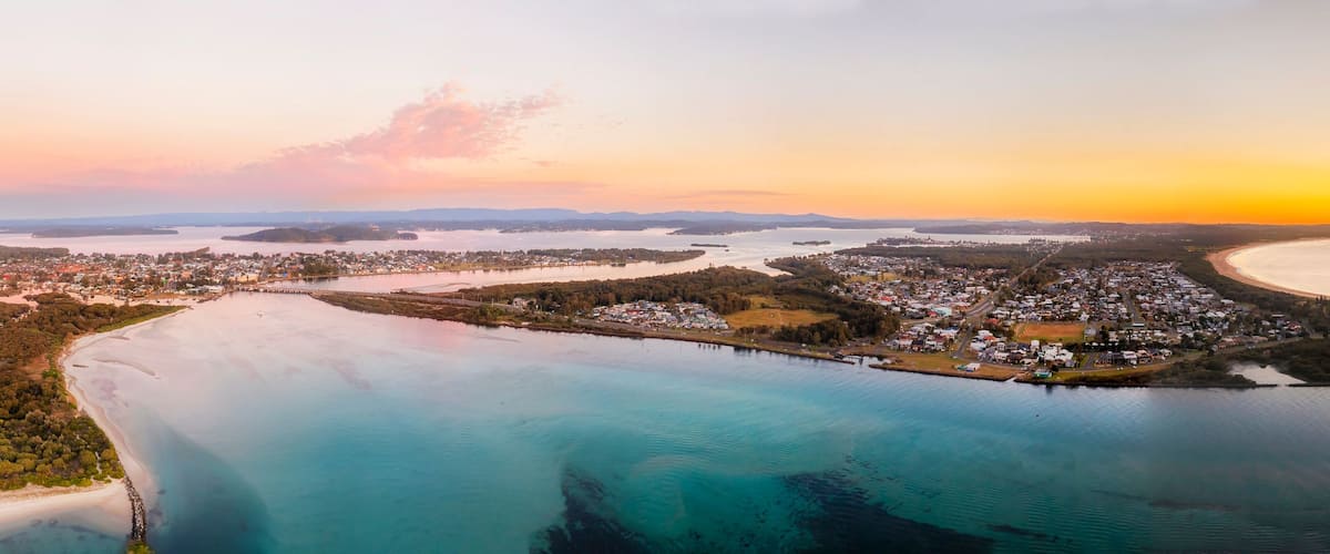 A coastal town with a bay, surrounded by forested areas and a large body of water.