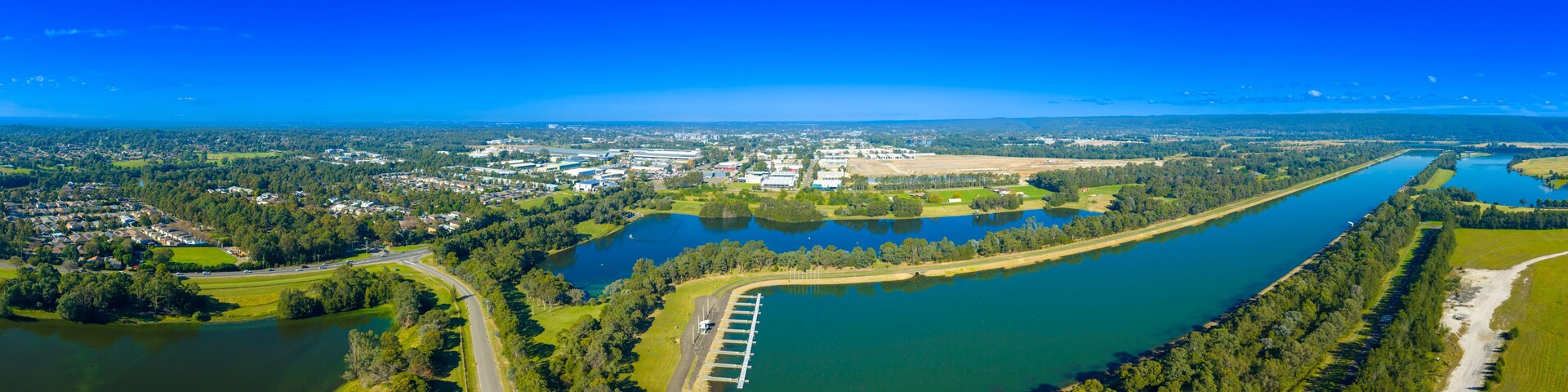 An aerial view of a river with a lock system, surrounded by residential areas and industrial buildings.