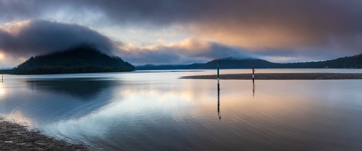 A calm lake with a forested island and two buoy markers.