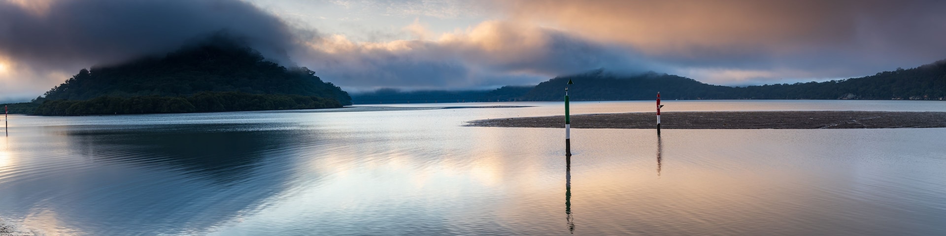 A calm lake with a forested island and two buoy markers.