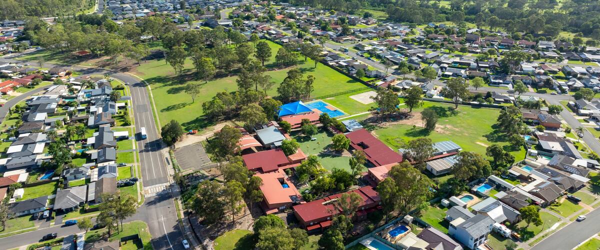 An aerial view of a residential area with houses, roads, and green spaces.