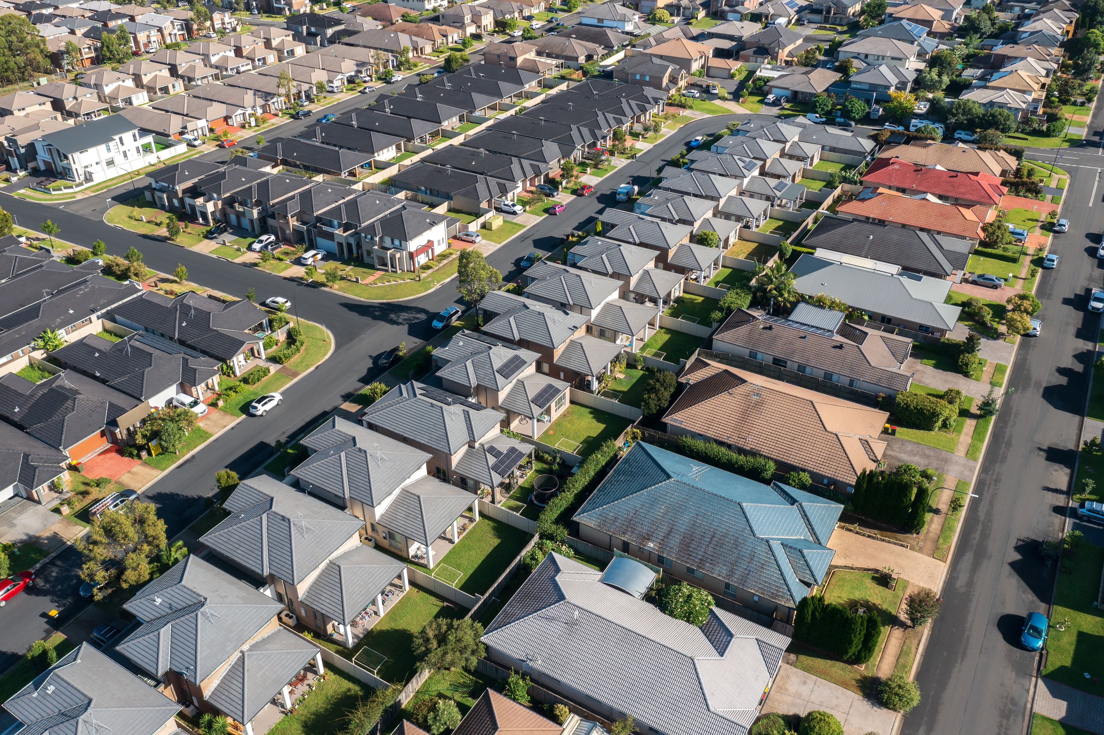 Um bairro residencial com várias casas, ruas e carros.