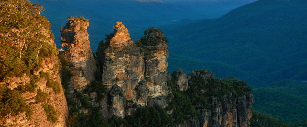 A canyon with prominent rock formations and a distant mountain range.