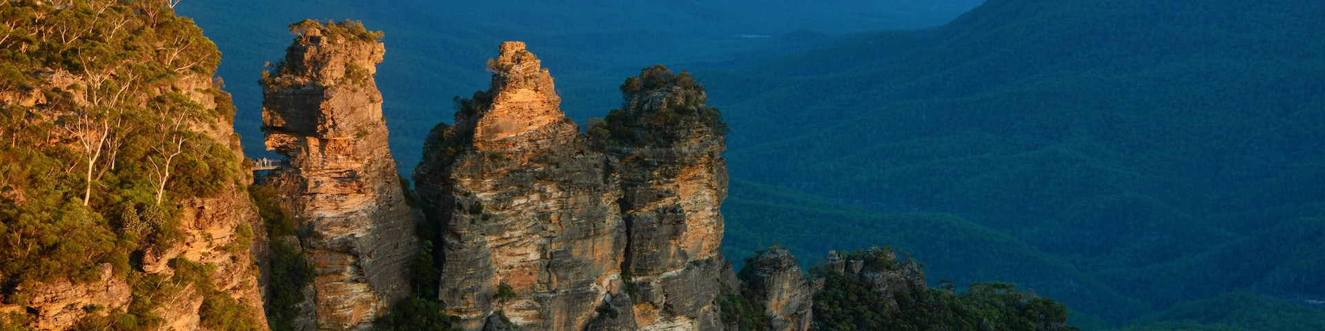 A canyon with prominent rock formations and a distant mountain range.