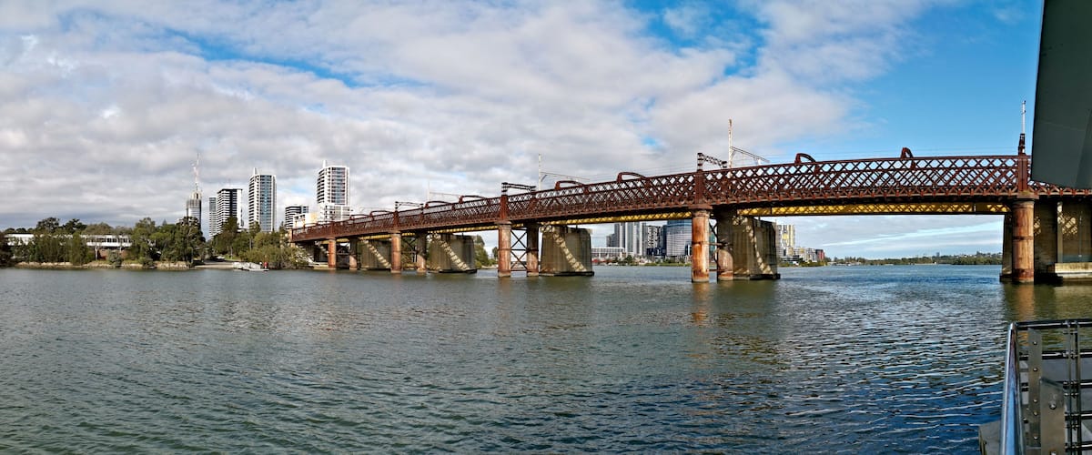 A bridge over water with a city skyline in the background.