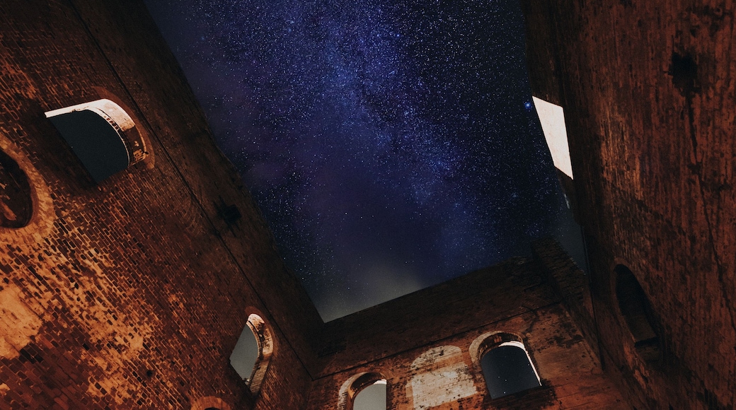 A starry night sky viewed through a brick structure with circular openings.