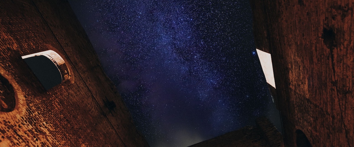 A starry night sky viewed through a brick structure with circular openings.