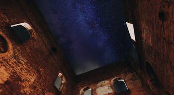 A starry night sky viewed through a brick structure with circular openings.