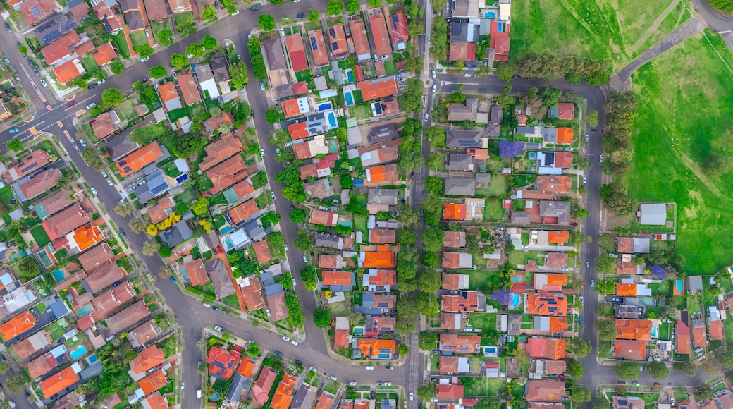 An aerial view of a residential area with houses, roads, and green spaces.