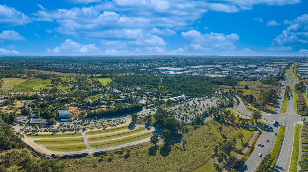 An aerial view of a suburban area with a mix of residential buildings, green spaces, and a highway.