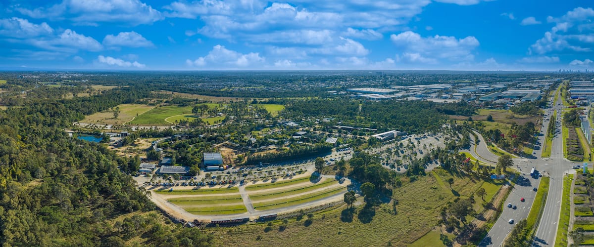 An aerial view of a suburban area with a mix of residential buildings, green spaces, and a highway.