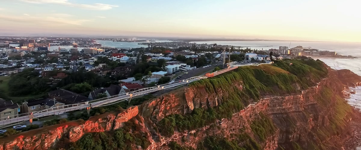 A coastal cityscape with a prominent cliff and a bridge.