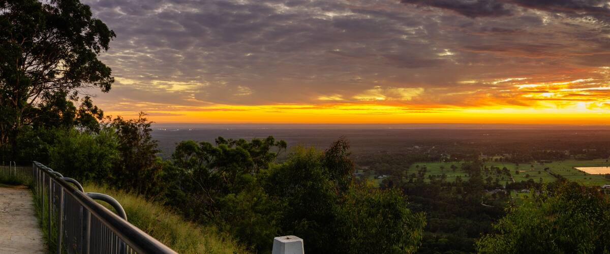 A panoramic landscape with a sunset, a river, and a forested area.