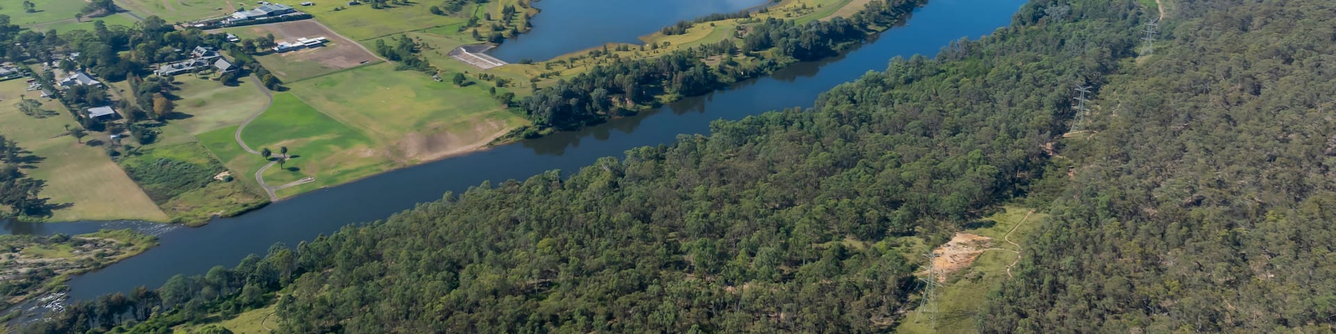 A river winding through a forested landscape with several ponds and a small settlement.