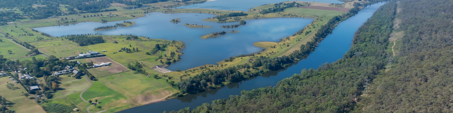 A river winding through a forested landscape with several ponds and a small settlement.