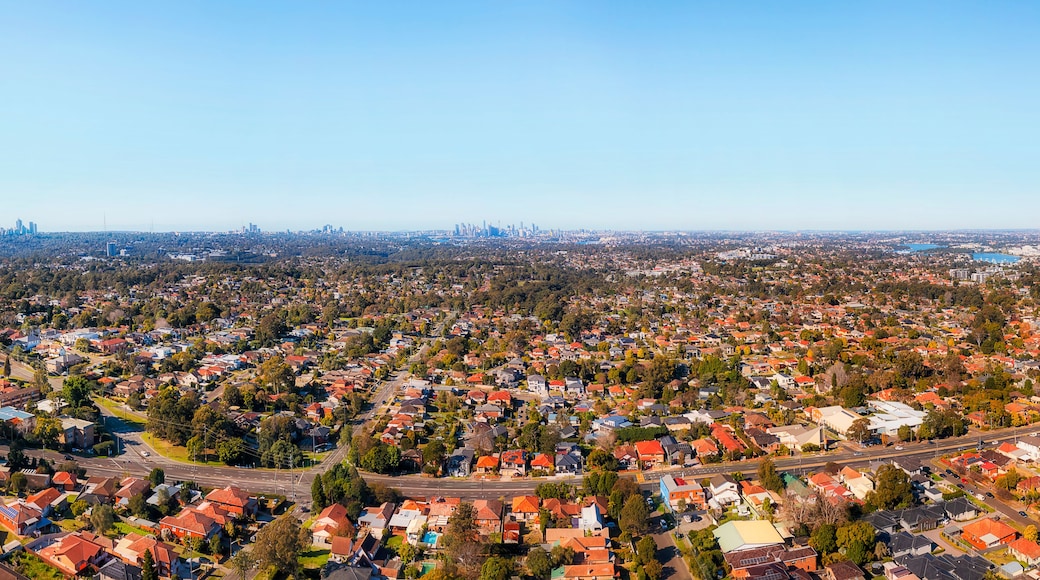 A densely populated urban area with a mix of residential and commercial buildings, a prominent highway, and a distant city skyline.