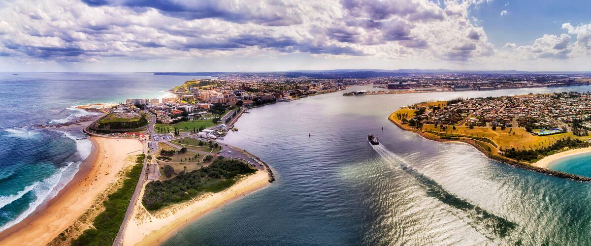 Una ciudad costera con playa, río y una zona urbana densa.