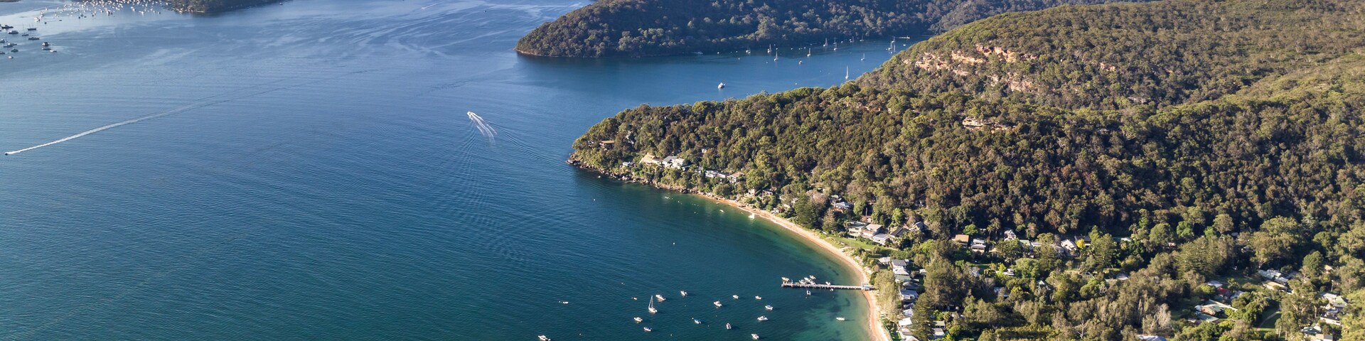 Aerial drone view of Great Mackerel Beach and Wharf on the western shores of Pittwater in Ku-ring-gai Chase National Park, Sydney, NSW, Australia. Mackerel can be reached via ferry from Palm Beach.