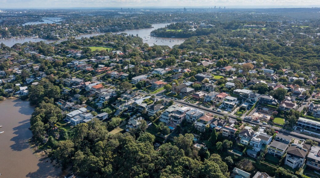 An aerial view of a coastal town with dense housing, a river, and a bridge.