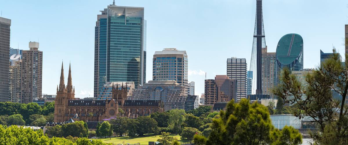 A city skyline with modern skyscrapers, a historic church, and a tall tower.
