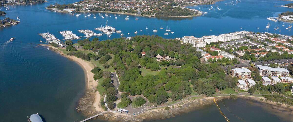 A coastal cityscape with a marina, residential areas, and a distant city skyline.