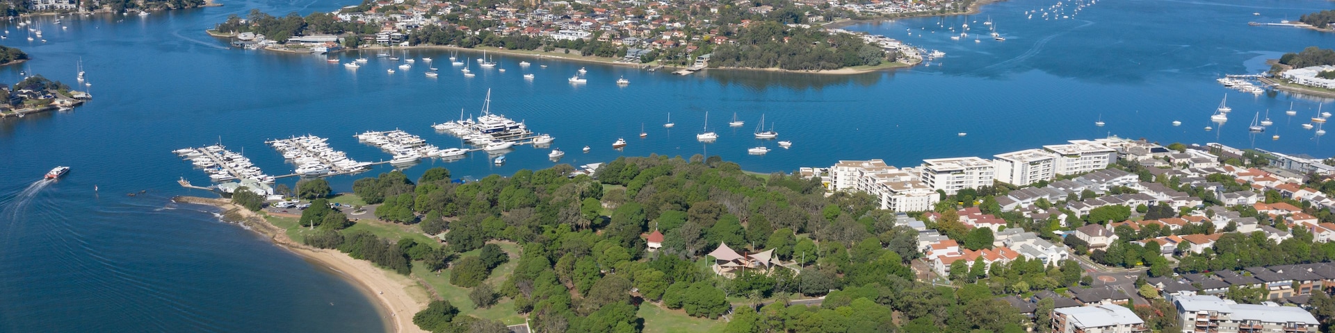 A coastal cityscape with a marina, residential areas, and a distant city skyline.