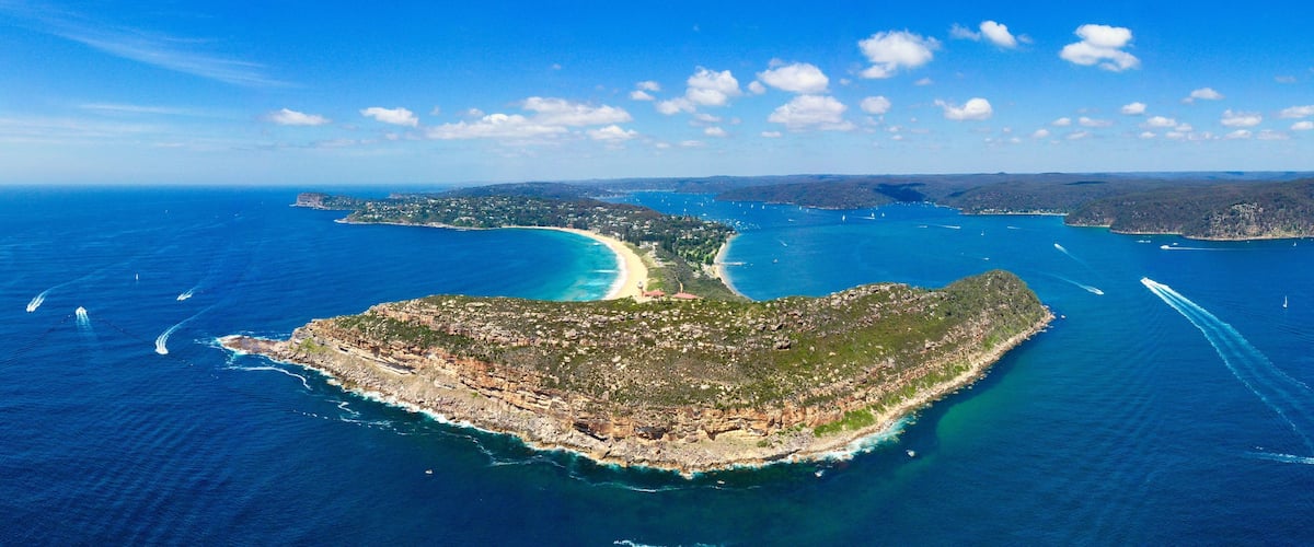 A coastal landscape with a prominent peninsula, clear blue waters, and distant islands.