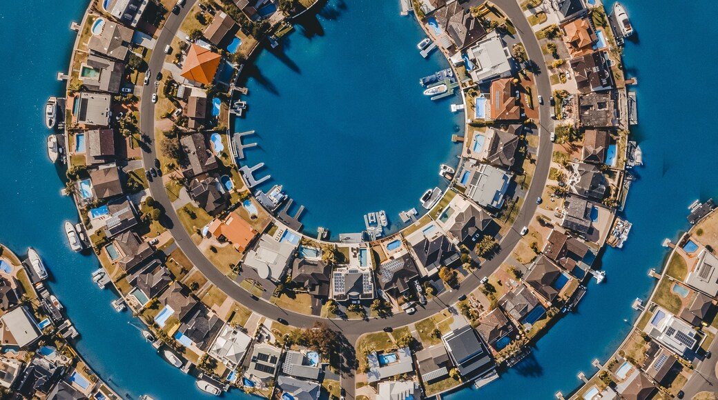 A coastal residential area with a circular layout of houses and boats docked along the waterfront.