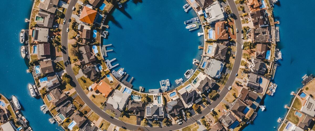 Un quartier résidentiel situé sur la côte, caractérisé par une disposition circulaire des maisons et des bateaux amarrés le long du littoral.