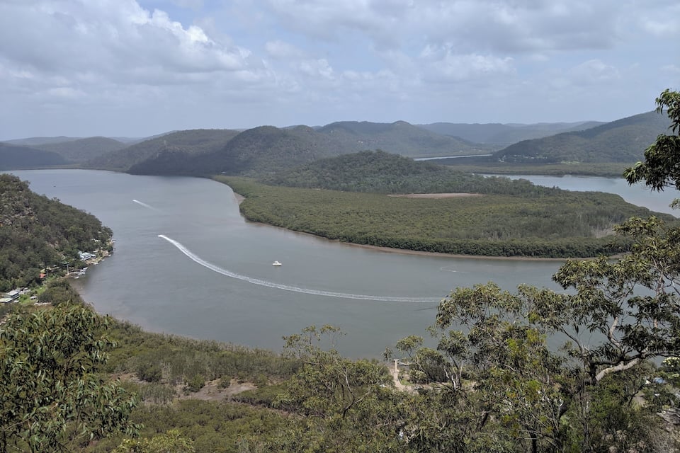 A river winding through a mountainous landscape with dense forests and a small settlement along the banks.