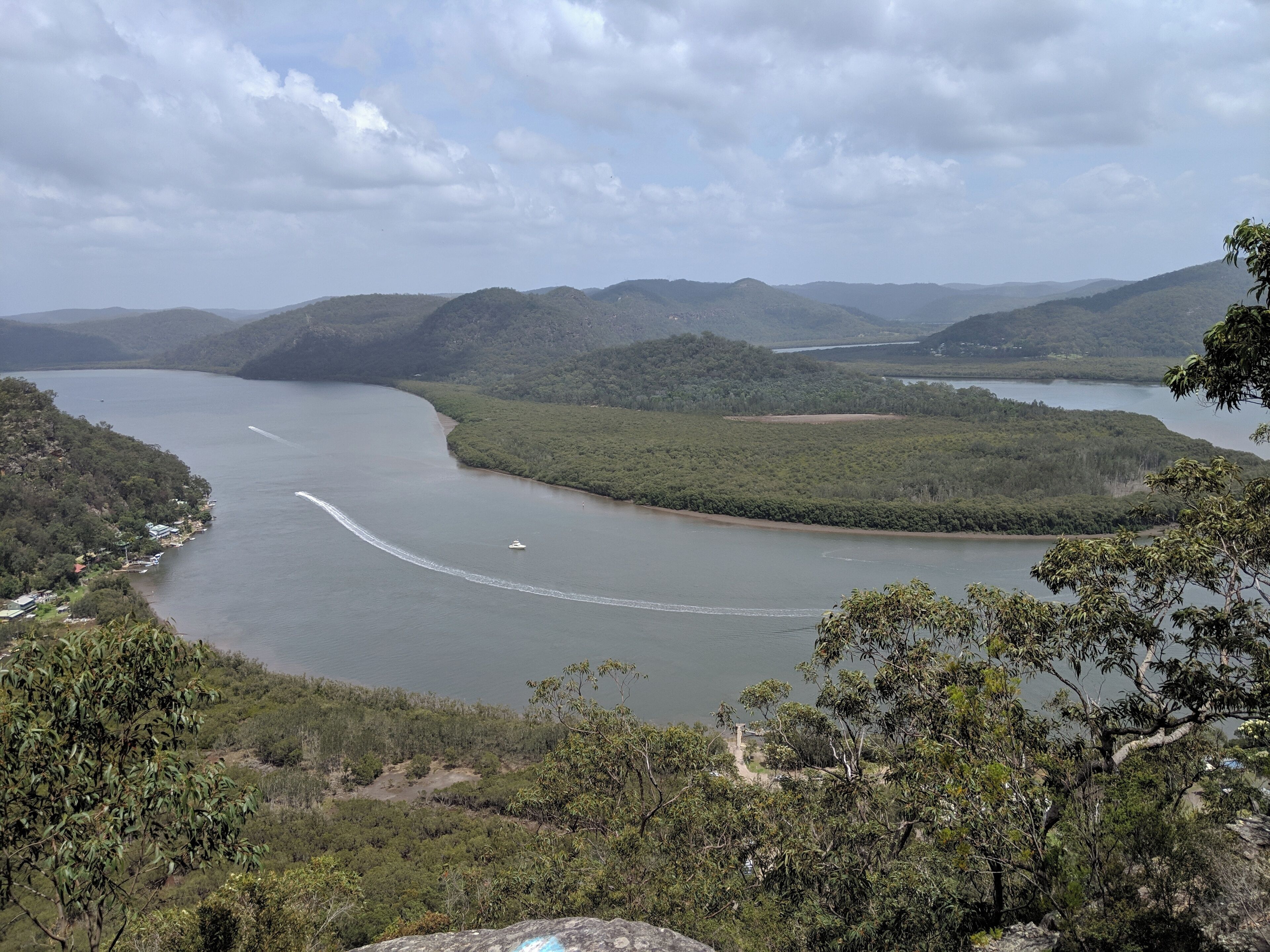 A river winding through a mountainous landscape with dense forests and a small settlement along the banks.